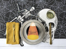 A styled Halloween table setting featuring a central place setting with a candy corn plate, a yellow napkin with a gold fork, a skull-shaped placemat, skeleton cutouts, and a spiderweb-patterned backdrop.