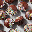 Chocolate cupcakes with sprinkles on a white surface