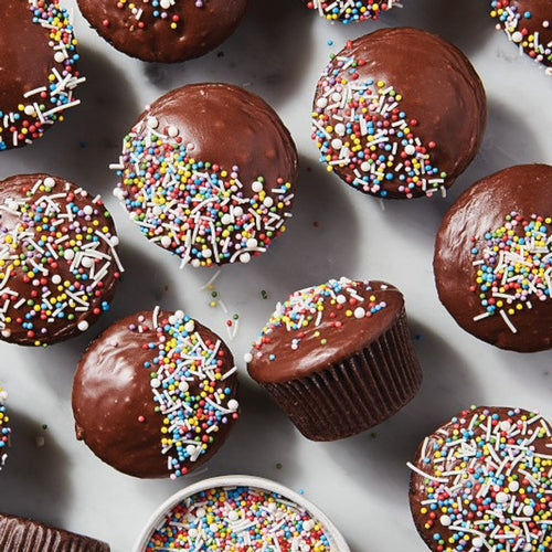 Chocolate cupcakes with sprinkles on a white surface