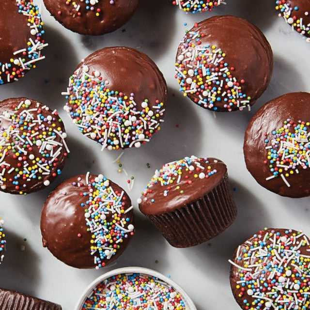 Chocolate cupcakes with sprinkles on a white surface