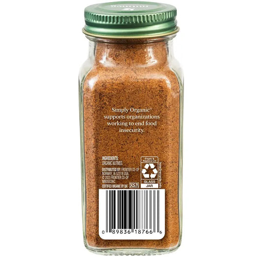 A glass spice jar filled with nutmeg, featuring a green metal lid and a white paper label with a barcode and product text, shown against a plain white background.