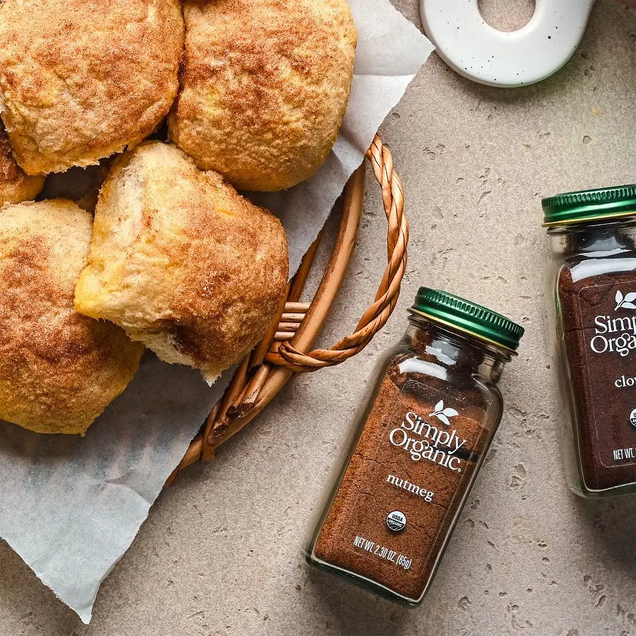 Baked goods in a basket with jars of Simply Organic spices on a stone surface