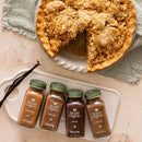 Apple pie with a slice missing, with four bottles of Simply Organic spices placed on a white plate.
