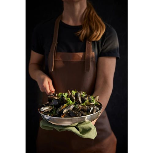 Person holding a pry pan of mussels with a dark background