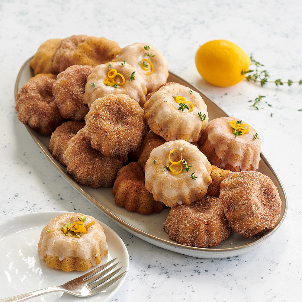 Assorted bundt cakes on a platter with a lemon and thyme garnish.