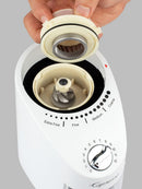 White coffee grinder with adjustable settings being held by a hand on a gray background