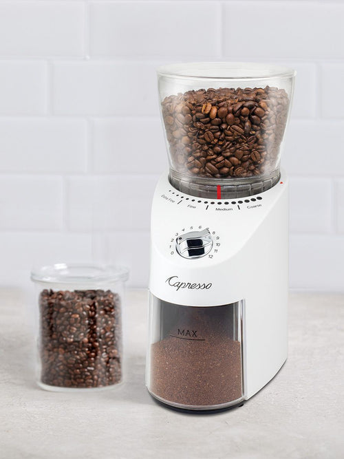 Coffee grinder with coffee beans and ground coffee on a light background