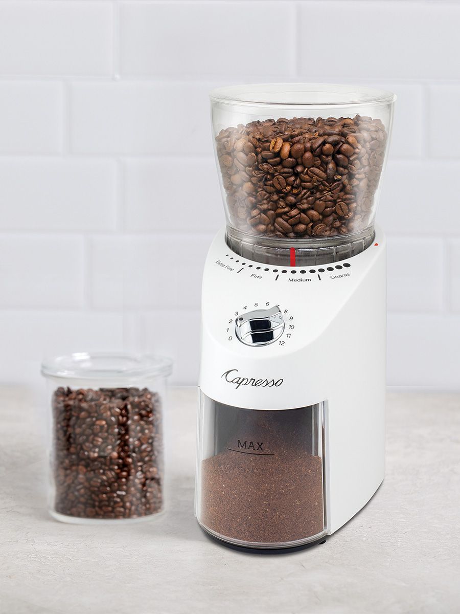 Coffee grinder with coffee beans and ground coffee on a light background