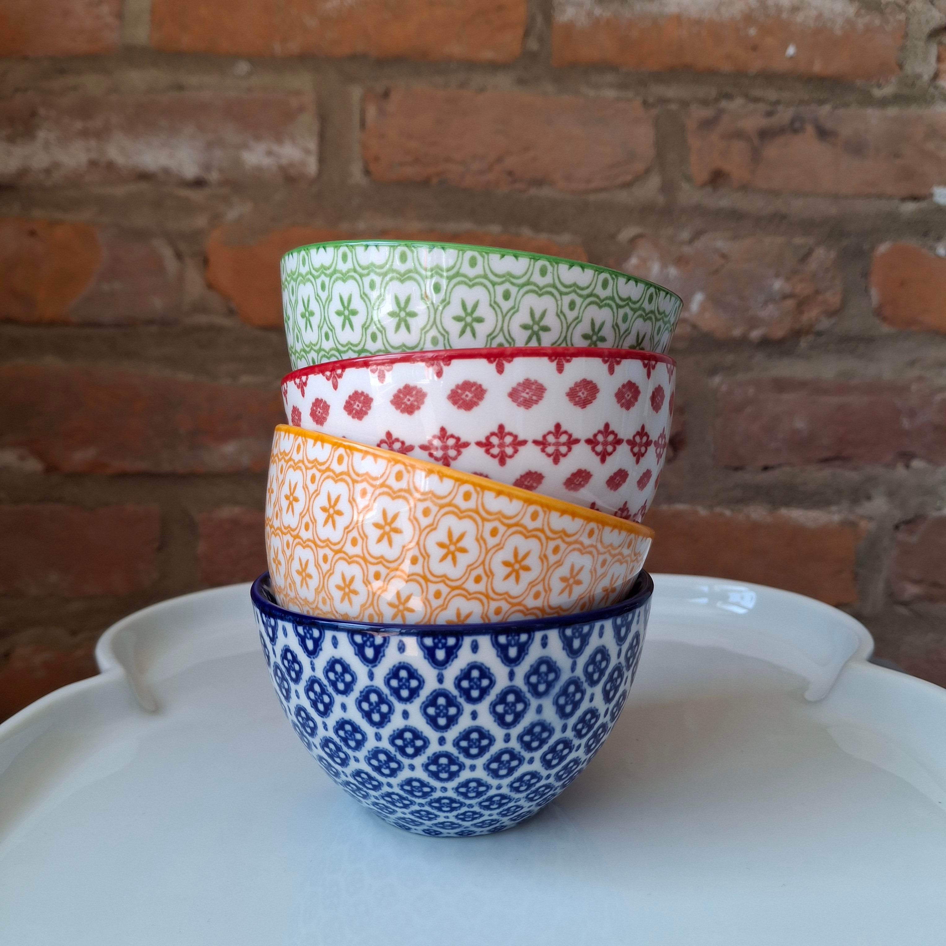 Stack of colorful patterned bowls against a brick wall.