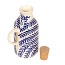 Ceramic oil bottle with blue leaf pattern and cork stopper on a white background