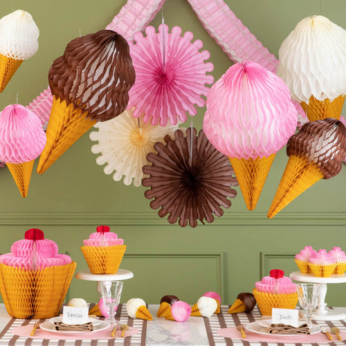 Decorative ice cream cone and cupcake themed party setup with hanging decorations and tableware.