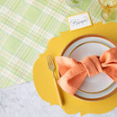 Elegant table setting with orange napkin and gold fork on a green plaid table runner.