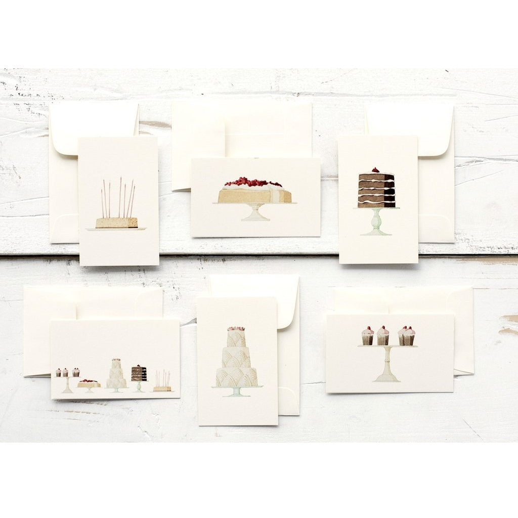 Set of greeting cards with cake illustrations on a white wooden surface