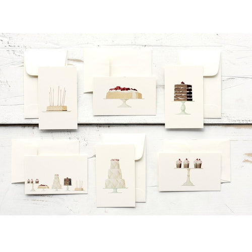 Set of greeting cards with cake illustrations on a white wooden surface