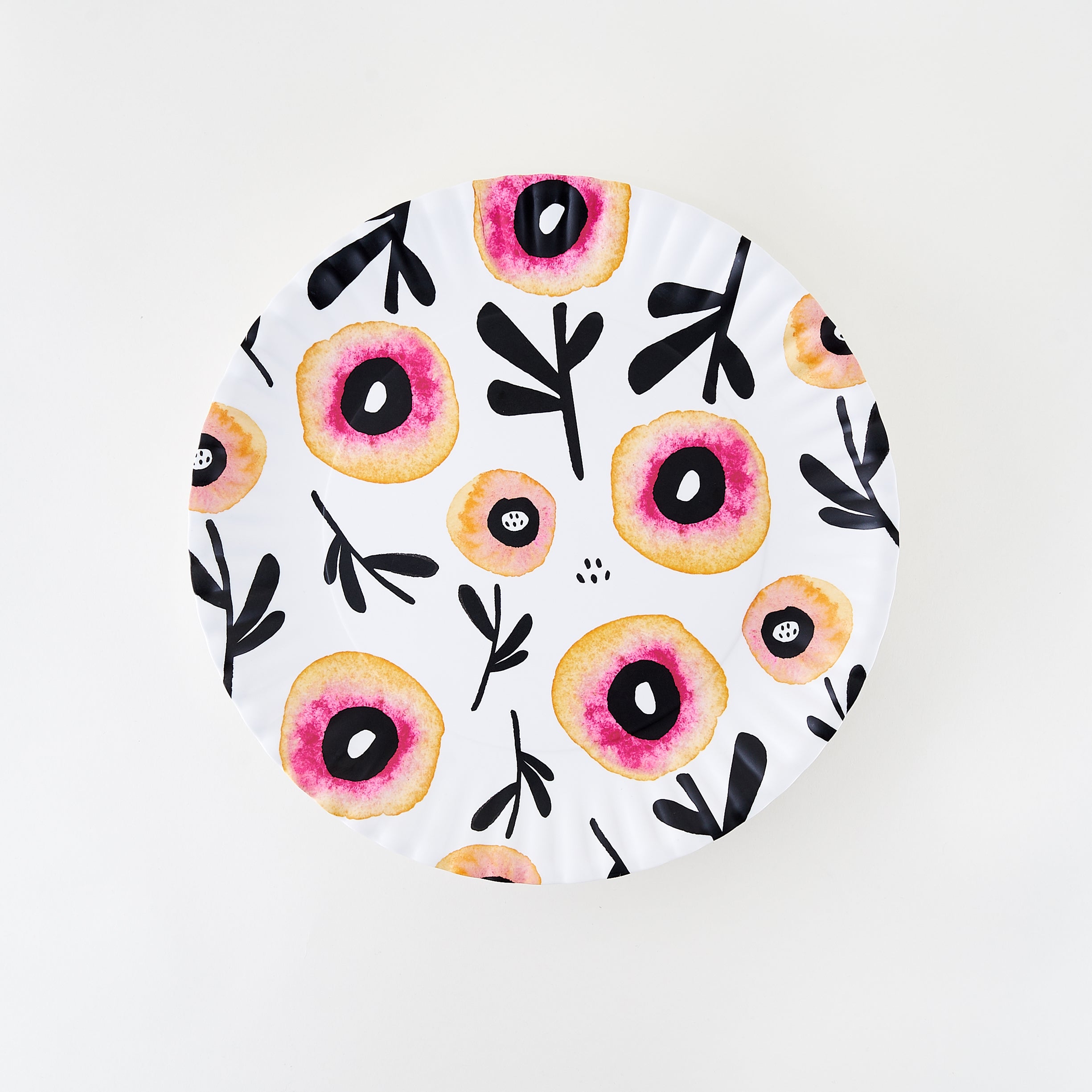 A white melamine platter with floral patterns in red, pink, and yellow hues and crimped edges.
