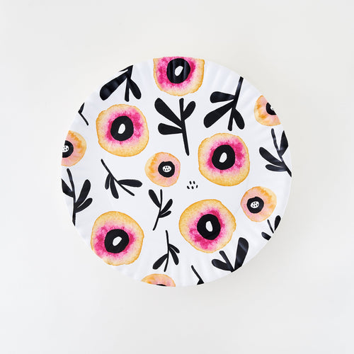 A white melamine platter with floral patterns in red, pink, and yellow hues and crimped edges.