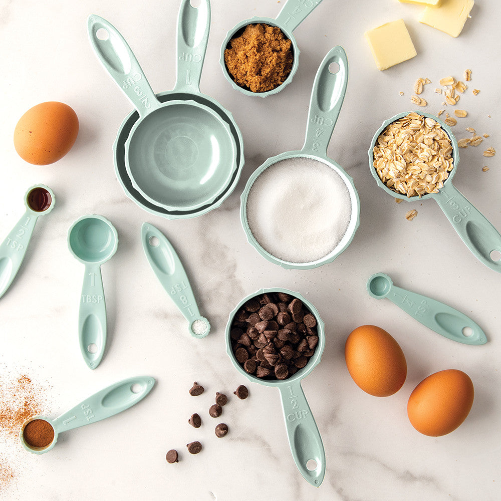 Set of measuring cups and spoons with ingredients on a marble surface