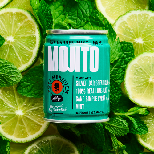 A can of Mojito by Post Meridiem surrounded by fresh lime slices and mint leaves. 