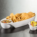 A white ceramic party snack platter filled with tortilla chips and a dipping bowl, shown on a gray wood-textured surface.
