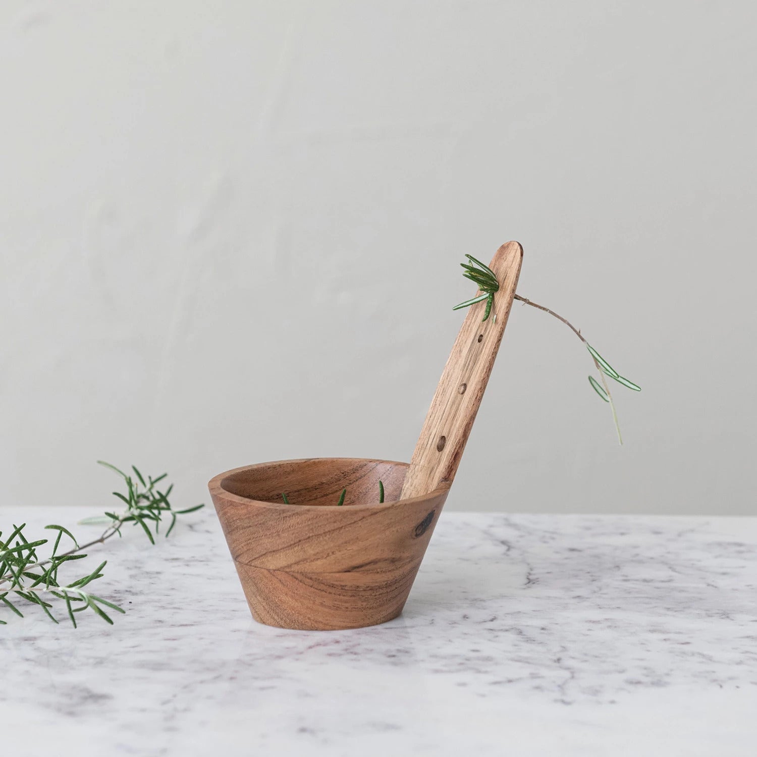 Wooden herb stripper with rosemary on a marble surface
