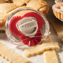 A red adjustable pastry trimmer among pieces of dough and a pie.