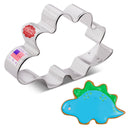 Metallic stegosaurus-shaped cookie cutter with a finished example cookie on a white background