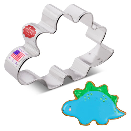 Metallic stegosaurus-shaped cookie cutter with a finished example cookie on a white background