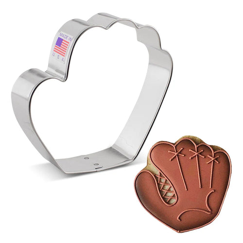 A steel cookie cutter in the shape of a baseball glove next to a cookie decorated with icing to resemble a baseball glove