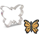 Butterfly-shaped cookie cutter next to a butterfly cookie on a white background