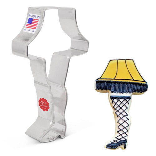 Cookie cutter shaped like the leg lamp from A Christmas Story with a yellow lamp shade and fishnet stockings, next to a decorated example cookie.