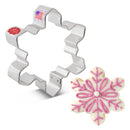 Snowflake cookie cutter with a decorated snowflake cookie on a white background