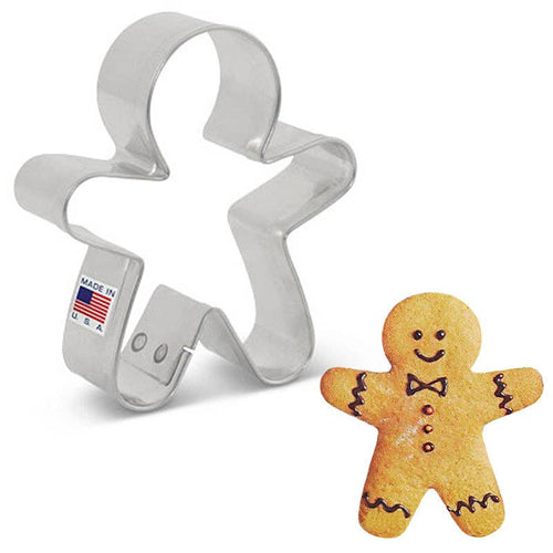 Metal cookie cutter shaped like a gingerbread man with a decorated gingerbread man next to it on a white background.