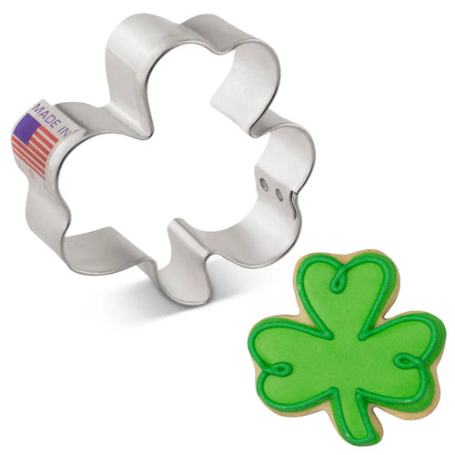 A small shamrock cookie cutter with an example cookie in the shape of a shamrock with green icing.