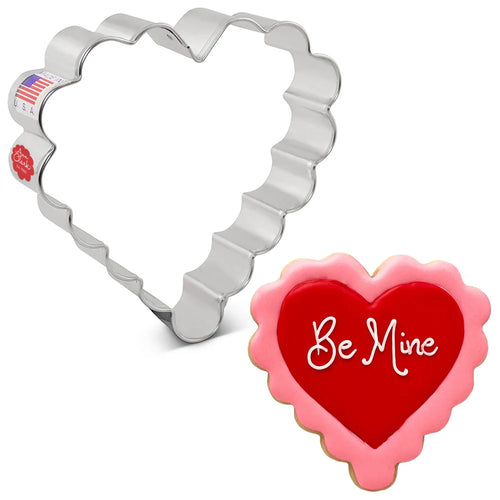 Heart-shaped cookie cutter with a heart-shaped cookie that says 'Be Mine'.