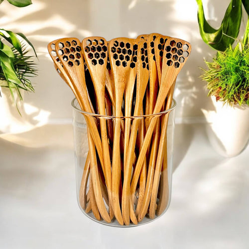 Set of wooden spoons with honeycomb pattern in a glass container on a light background
