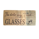 Wooden sign with engraved text and a wine glass symbol on a dark background