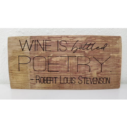 Wooden sign with engraved text 'Wine is bottled poetry. Robert Louis Stevenson' on a white background