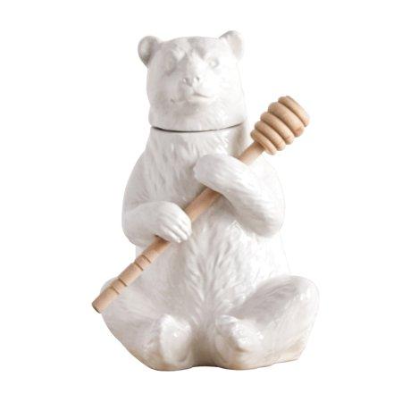 A white ceramic honey pot in the shape of a bear holding a bamboo honey dipper.
