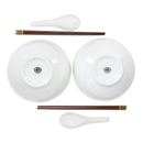 A white ceramic dinnerware set featuring two bowls shown from the bottom, two dark brown chopsticks with gold-toned ends, and two white spoons, arranged symmetrically on a white background.