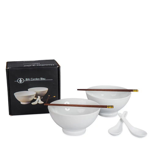 White ceramic bowl and spoon set with dark brown wooden chopsticks and gold-colored tips, shown with a black BIA Gordon Bleu branded box on a white background.