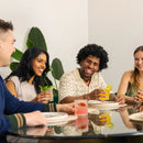 Four friends enjoying drinks together at a table with a plant in the background