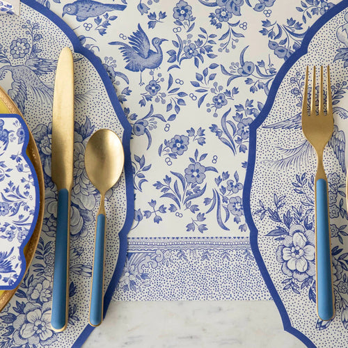 A close up of a place setting with blue and white table runner, knife, fork, and spoon.