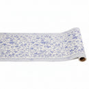 A rolled-up paper table runner with blue peacock patterns on a white background, designed by Hester & Cook.