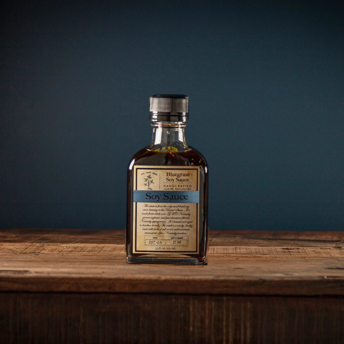 Bottle of soy sauce on a wooden surface with a dark background
