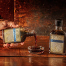 Person pouring soy sauce from a bottle into a small glass bowl on a wooden surface.