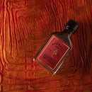 Bottle of Bourbon Smoked Bluegrass Soy Sauce on a textured red wood background