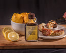 Bottle of Small Batch Bourbon Ponzu with lemons and food on a wooden board