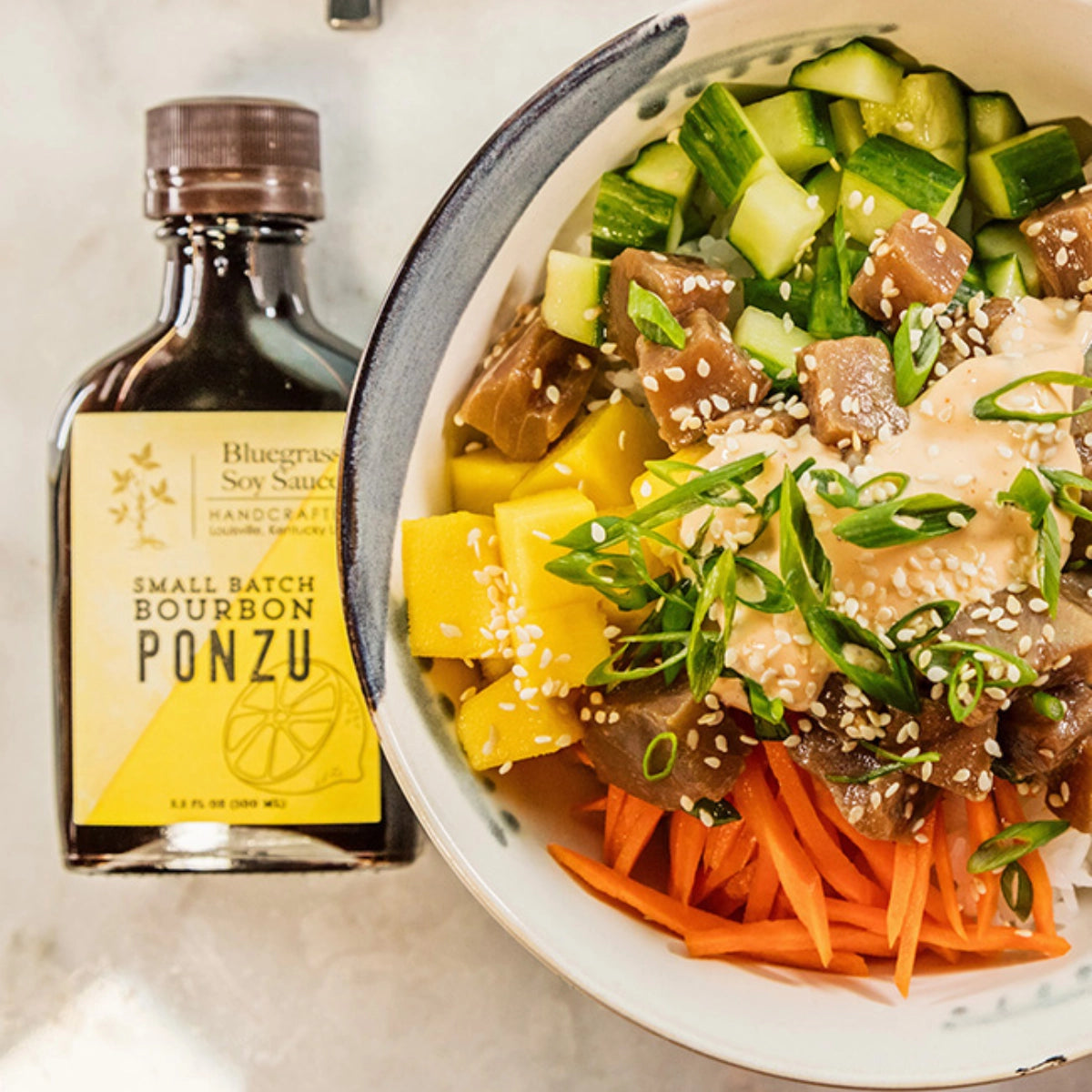 Bowl of vegetables and a bottle of Bluegrass Soy Sauce Ponzu on a light background