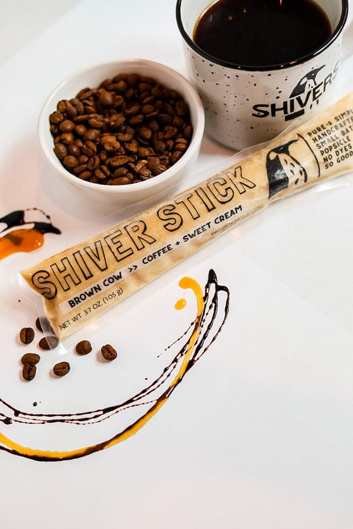 Shiver Stick with coffee beans and a cup of coffee on a white surface