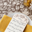 Decorative table setting with a floral patterned tablecloth, yellow napkin, and menu card.